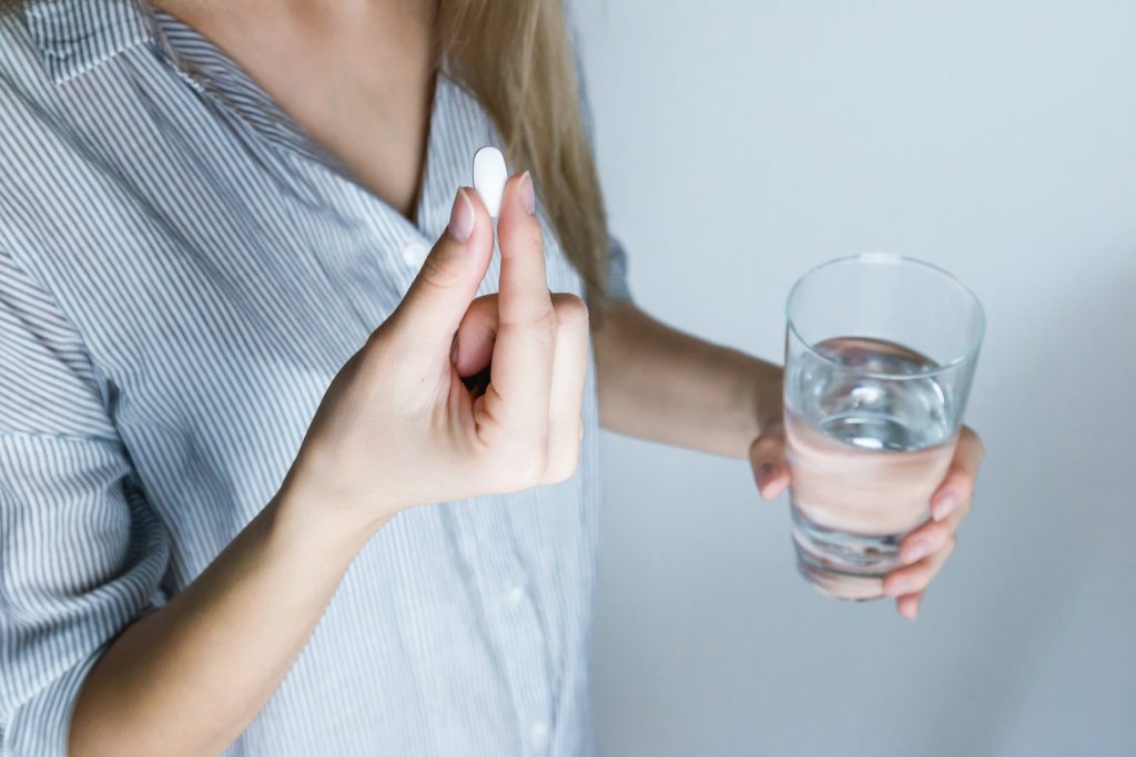 Cô gái uống thuốc aspirin - cách chữa nhiệt miệng