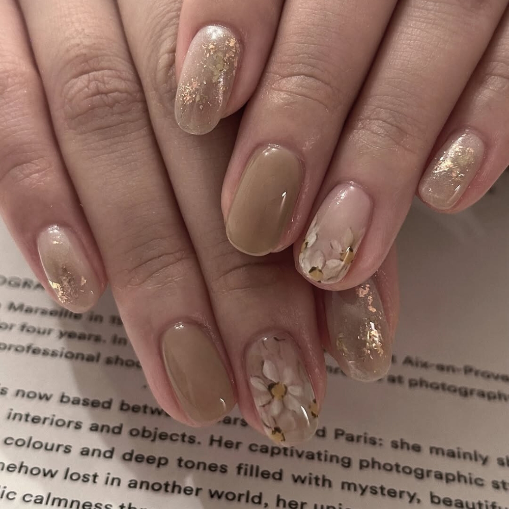 đôi tay với kiểu nail màu nâu trà sữa cùng họa tiết bông hoa