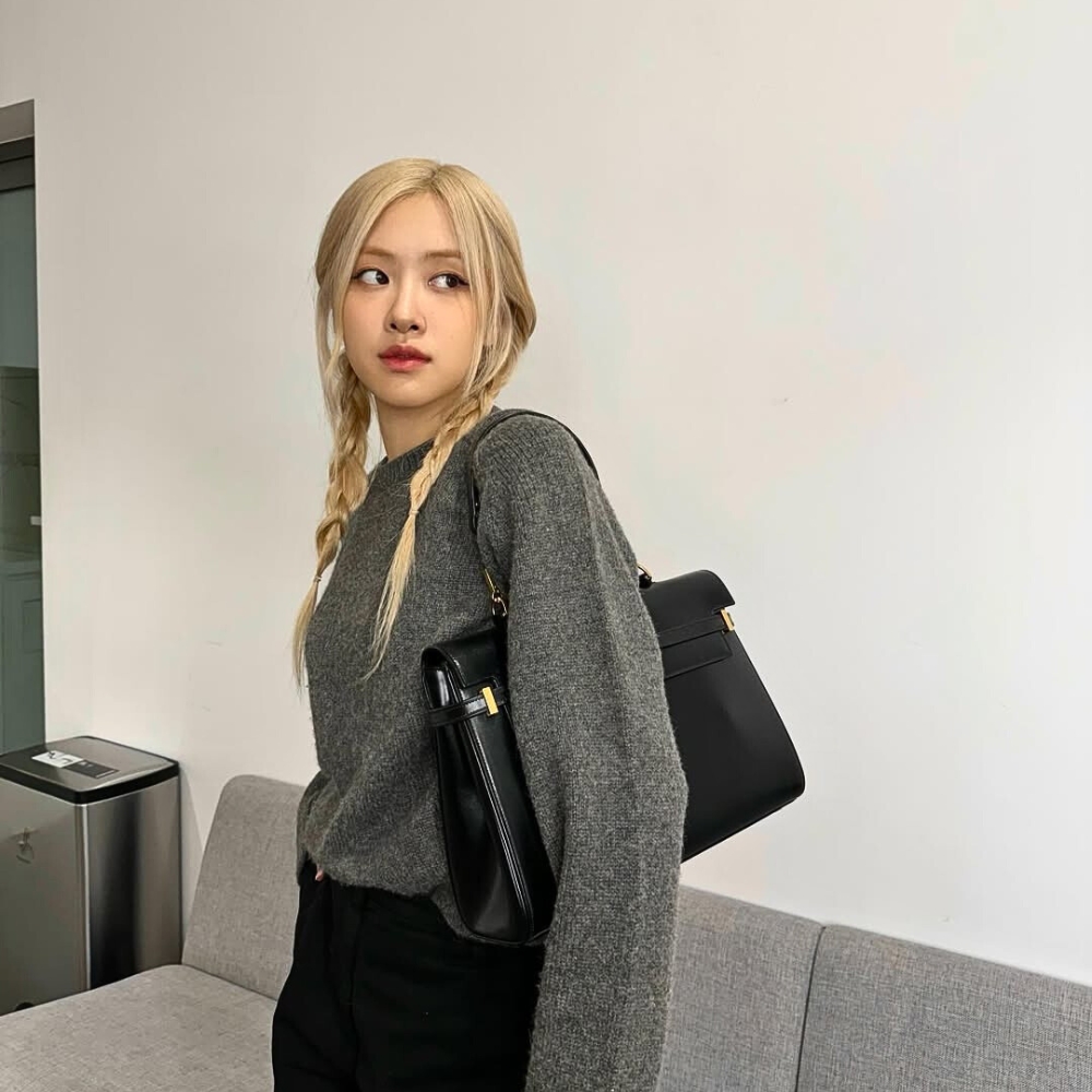 Giọng ca chính của BLACKPINK đeo túi xách đen và tết tóc 2 bên.