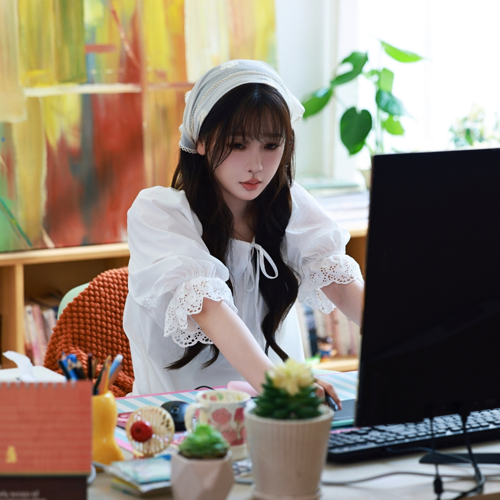 Ngu Thư Hân mang đầm trắng ngồi trước bàn máy tính.