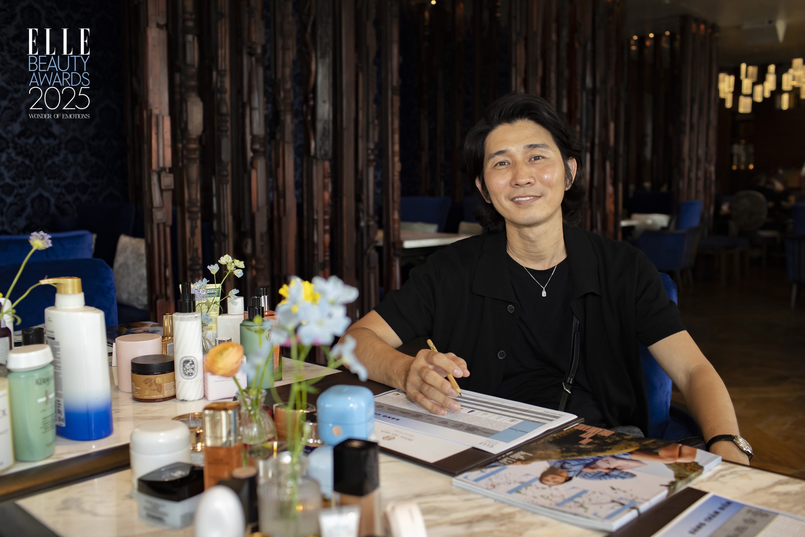 Markeup Artist Tùng Châu Trần ngồi tại bàn chấm điểm sản phẩm làm đẹp