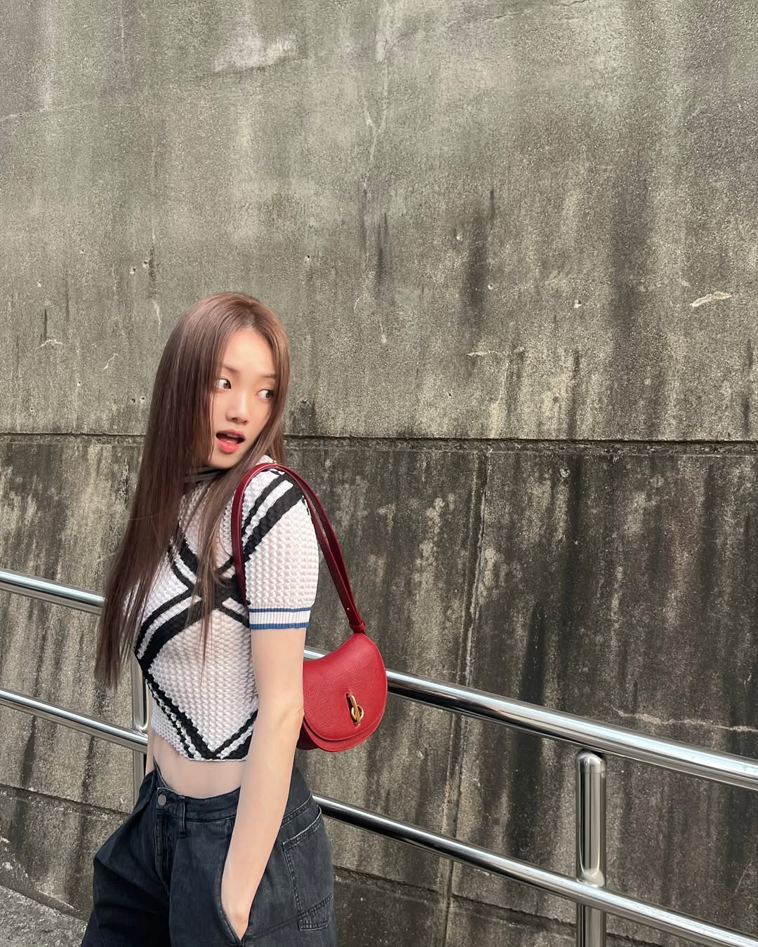Cô gái diện trang phục street style cá tính với áo lưới trắng viền đen và túi xách đỏ nổi bật, trang điểm tông cam đất nhẹ nhàng