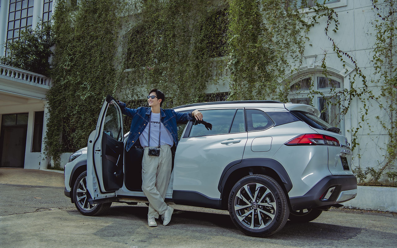 Chàng trai áo sơ mi xanh đứng bên cạnh xe Toyota