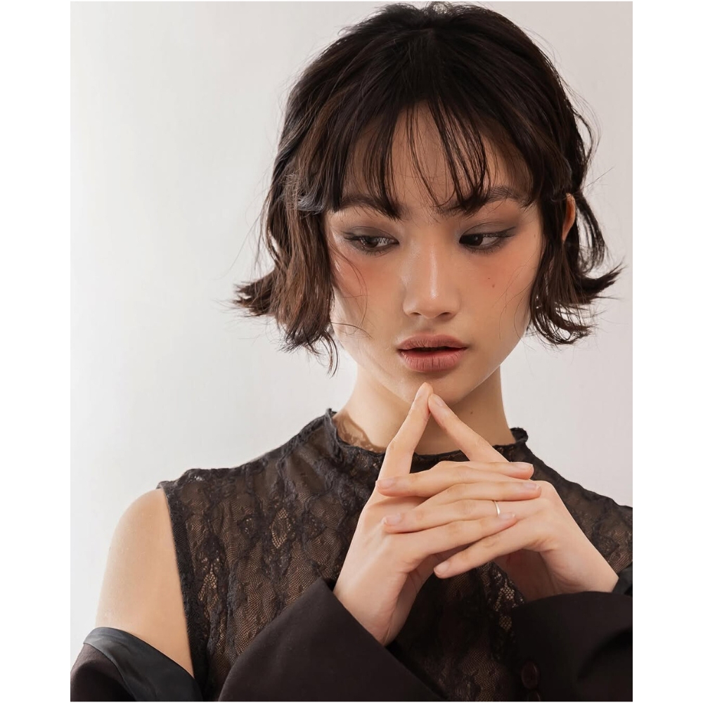 Cô gái tóc ngắn, trang điểm tone nâu trầm để hai ngón tay lên môi
