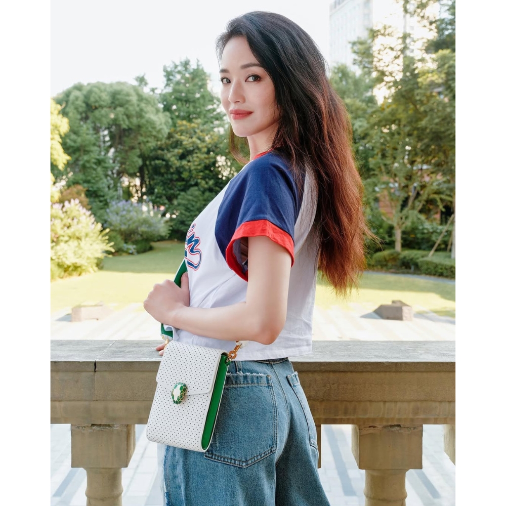 Thư Kỳ cầm túi xách bên ban công.