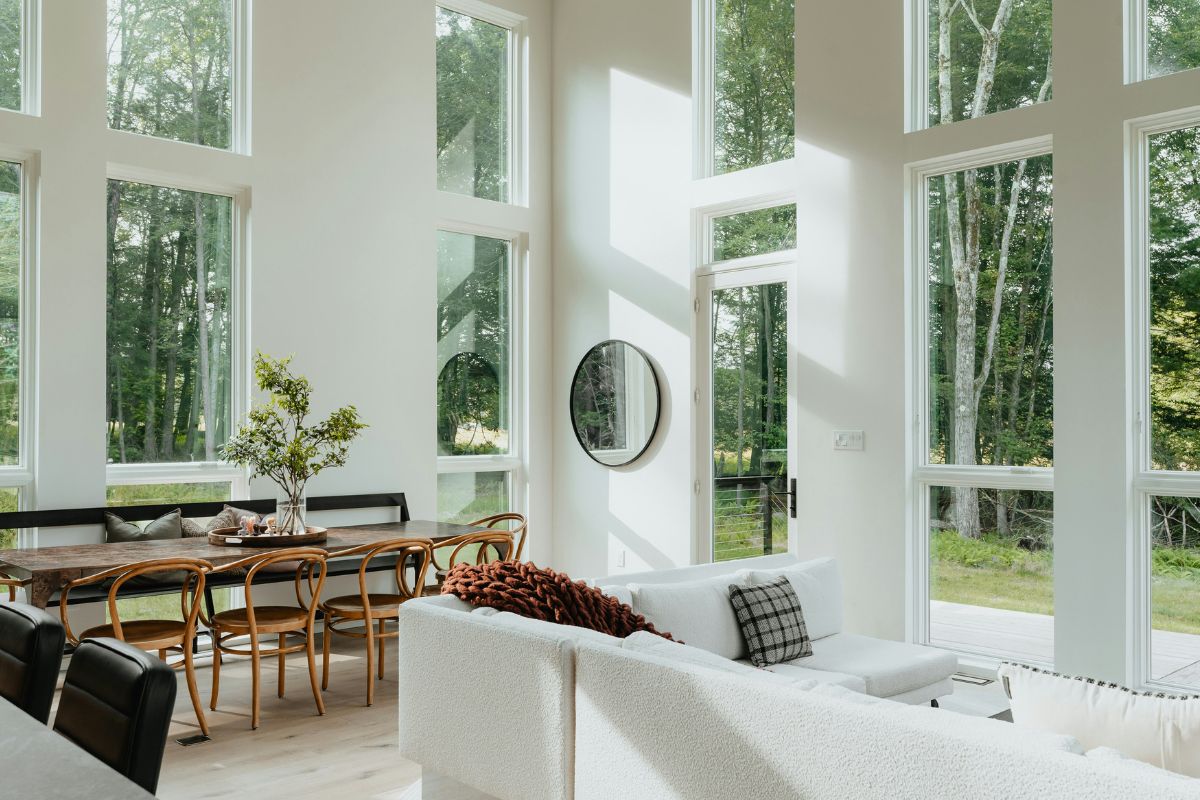Phòng khách phong thủy có concept màu trắng và cửa kính lớn nhìn ra rừng cây