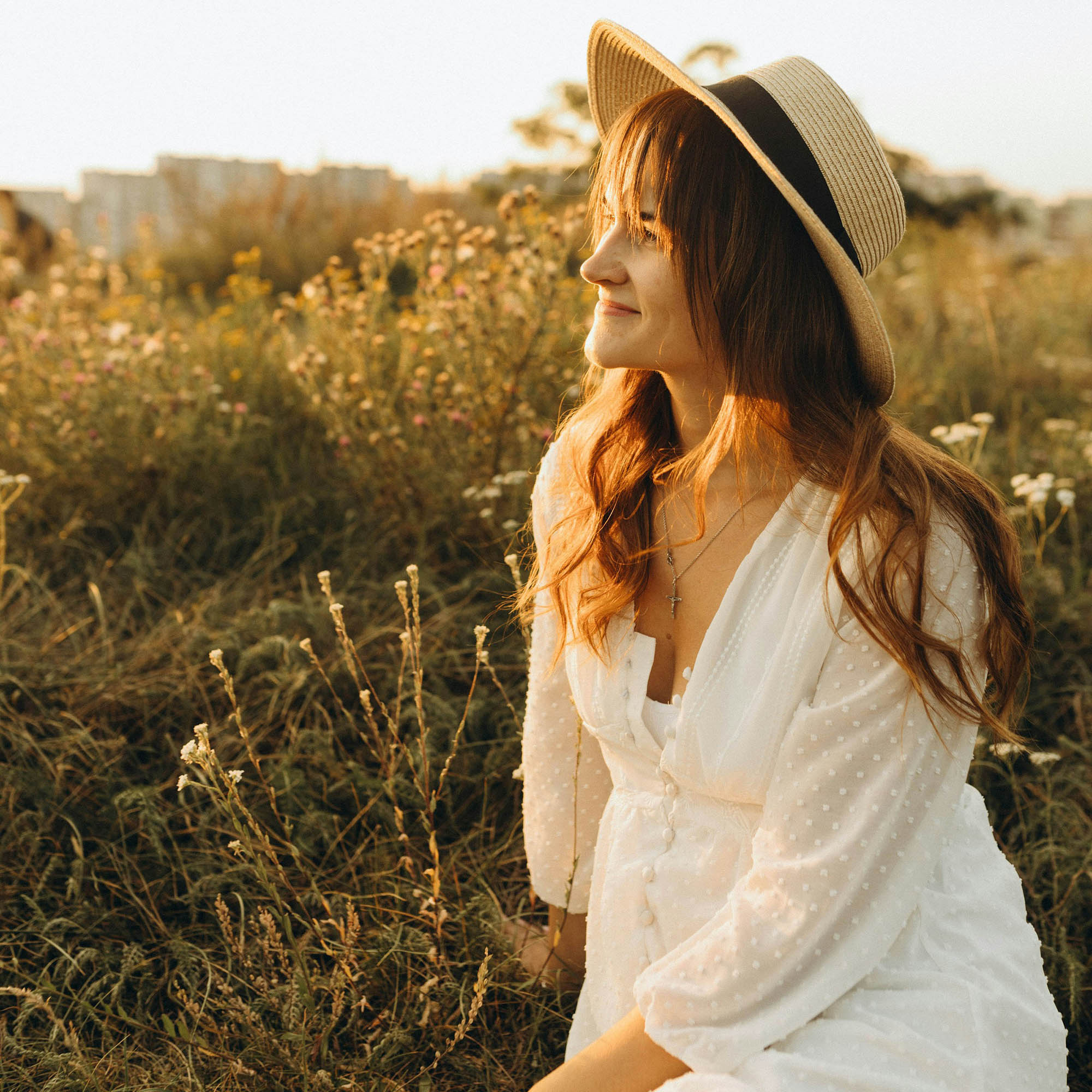 cô gái váy trắng ngồi giữa cánh đồng đang hạnh phúc