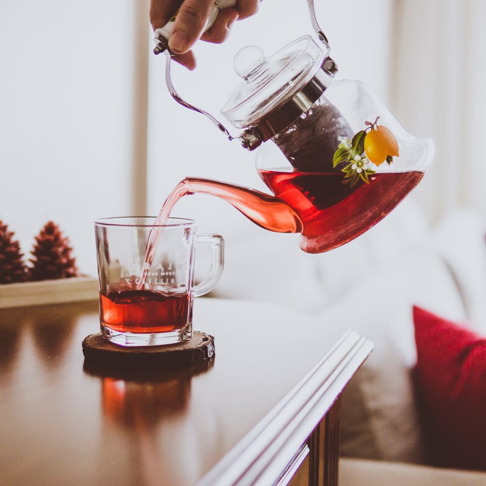 Hình ảnh trà atisô đỏ được đổ từ ấm nước vào ly.