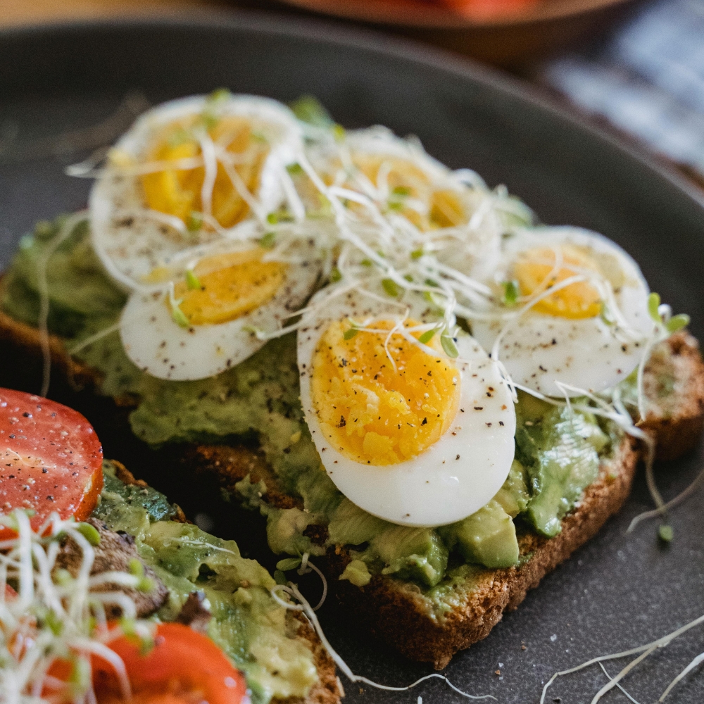 Bánh mì nướng bơ (avocado toast) được trang trí bằng hai quả trứng luộc vừa chín tới.