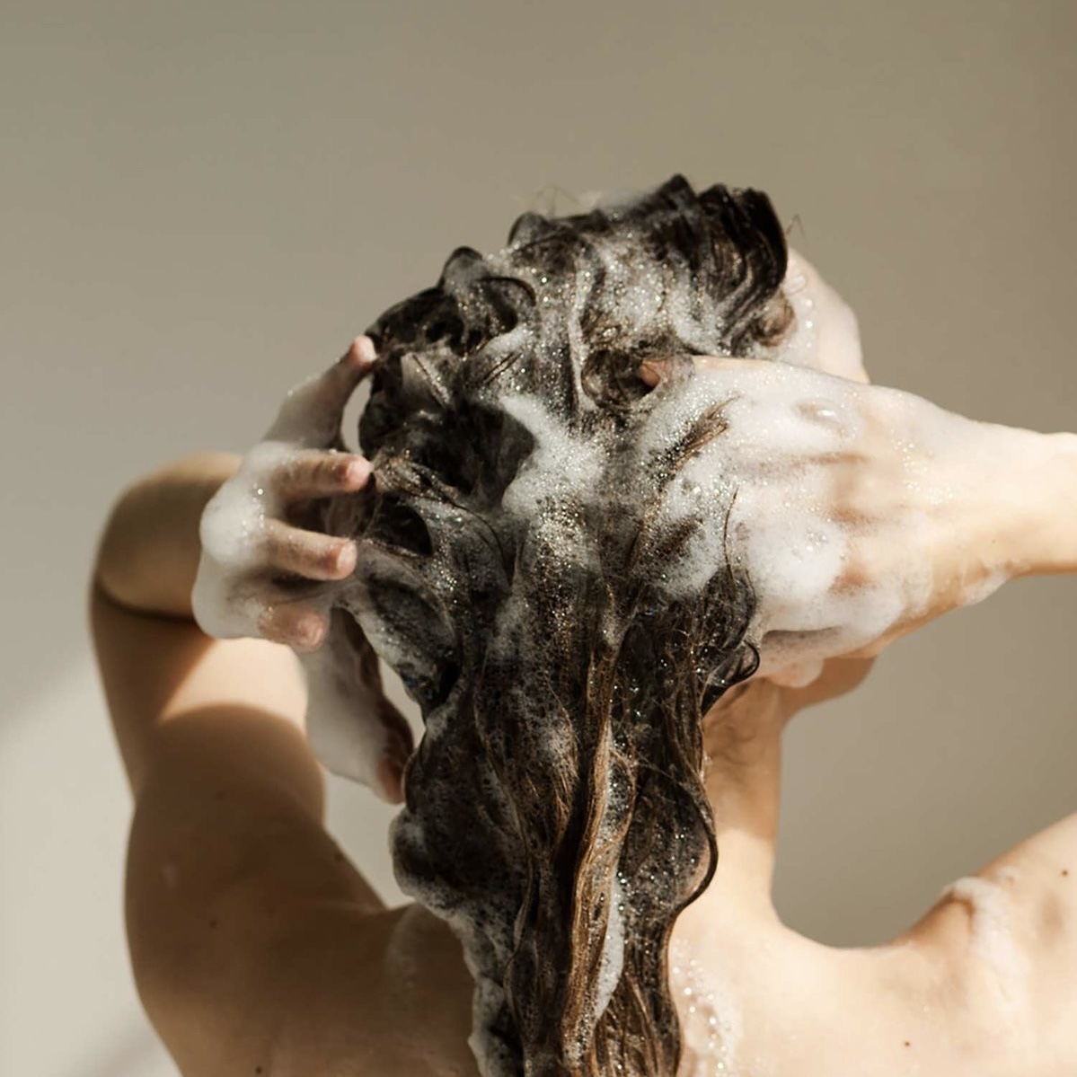Cô gái đang gội đầu không chứa sulfate giúp chăm sóc tóc.