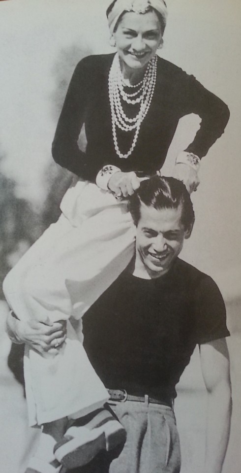 Coco Chanel cùng một người bạn. Bà mặc quần trắng và quấn khăn trên đầu, đeo chuỗi ngọc trai sau này trở thành huyền thoại.