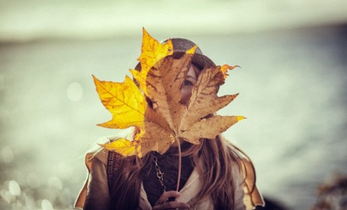 Girl holding giant leaf over face