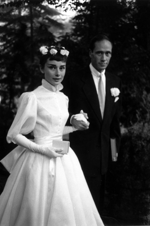Năm 1954, khi kết hôn lần đầu với Mel Ferrer, minh tinh màn bạc Audrey Hepburn chọn chiếc váy trắng, độ dài đến mắt cá và “kín cổng cao tường”. Điểm nhấn của bộ váy là hai tay được thiết kế bồng và những bông hoa điểm xuyết trên mái tóc theo phong cách vũ công ballet.
