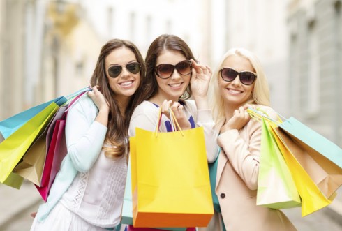 three smiling girls with shopping bags in ctiy