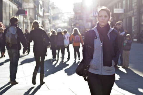 Urban girl standing out from the crowd at a city street.