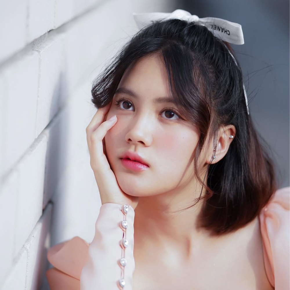 Diễn viên Minnie Phantira đặt tay lên má với lớp makeup trong trẻo.