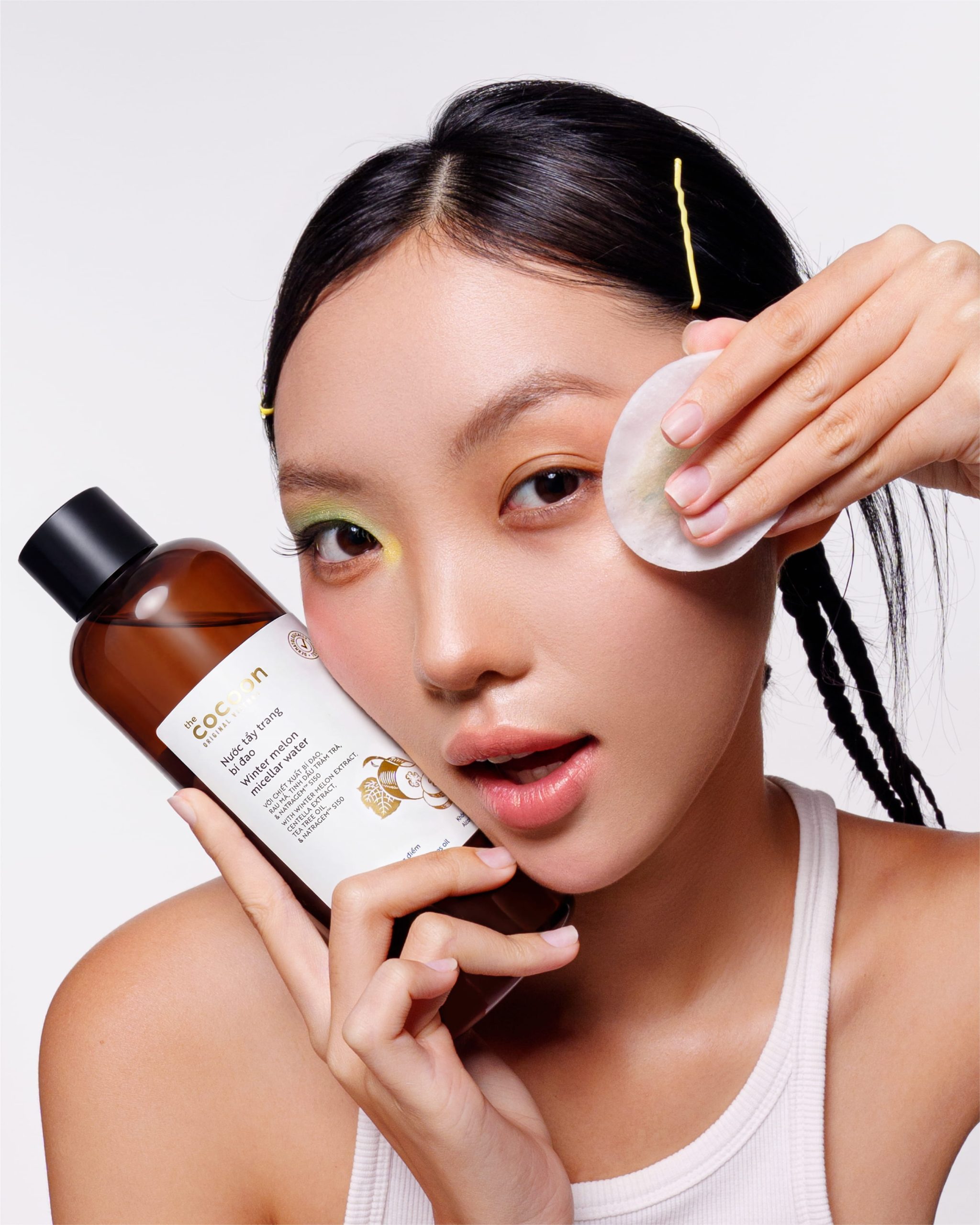 cô gái cầm chai nước tẩy trang và bông tẩy trang