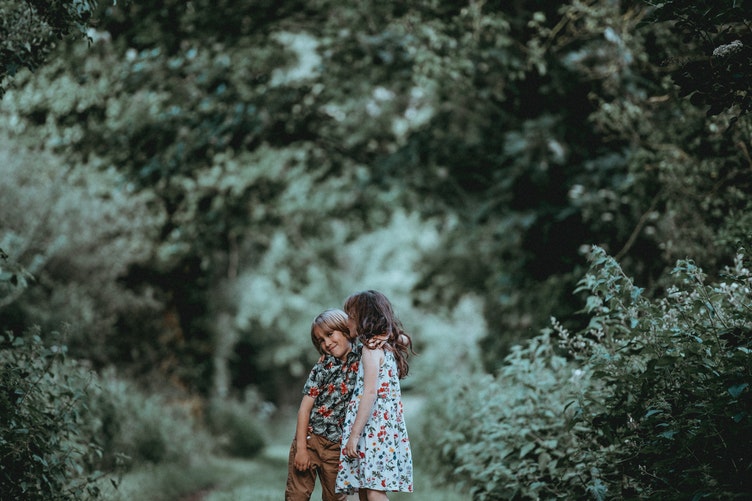 Bé gái hôn má bé trai trong vườn cây