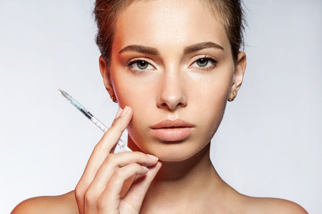 cô gái đẹp cầm kim tiêm botox