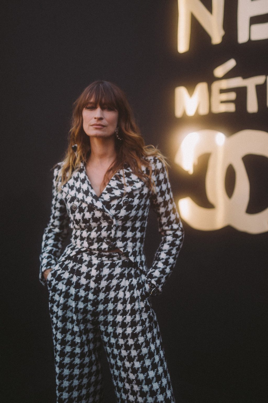 caroline de maigret mặc áo vest và quần caro trắng đen tại chanel's métiers d'art show