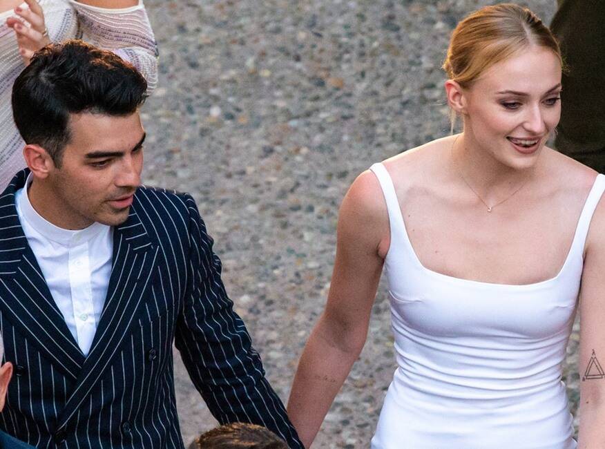 sophie turner mặc đầm trắng cổ vuông và joe jonas mặc vest đen sọc trắng tại buổi tiệc pre-wedding