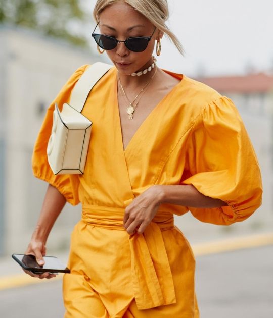 Fashionista mặc chiếc váy vàng cùng túi xách trắng và kính mắt đen