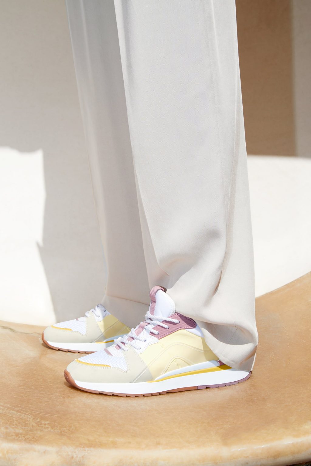 Người mẫu mặc quần dài trắng và đi giày sneaker