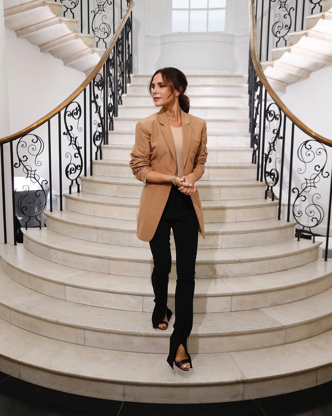 victoria beckham mặc áo khoác màu nâu và quần đen tuần lễ thời trang london