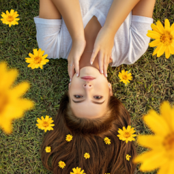 dầu dưỡng tóc cô gái áo trắng nằm trên hoa vàng cỏ xanh feature dọc