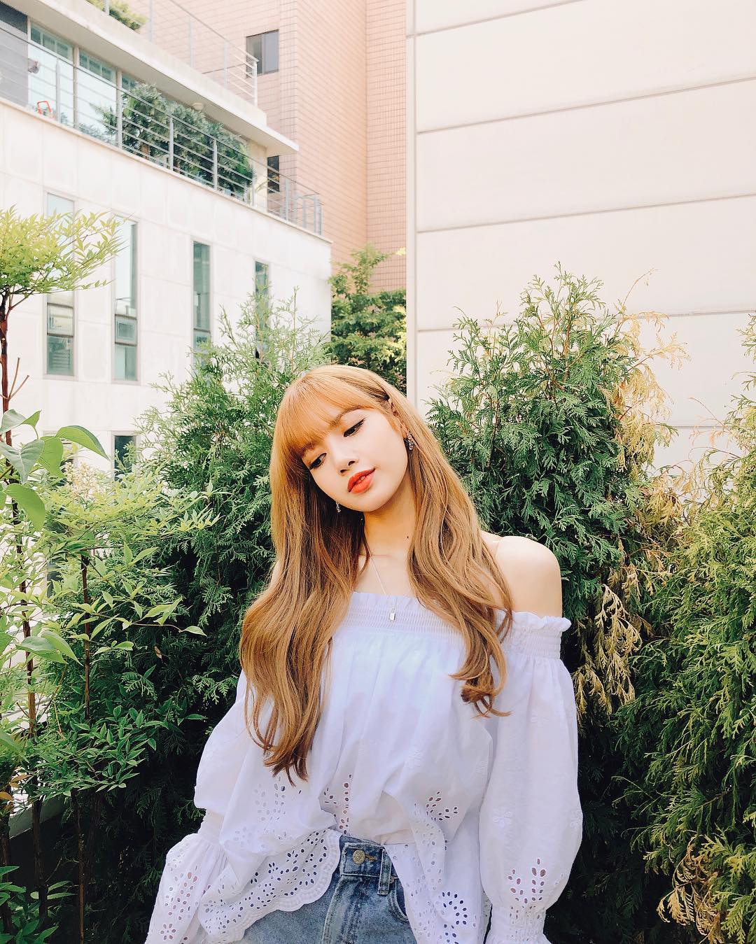 Lisa (Blackpink) mặc áo trễ vai màu trắng và quần jeans