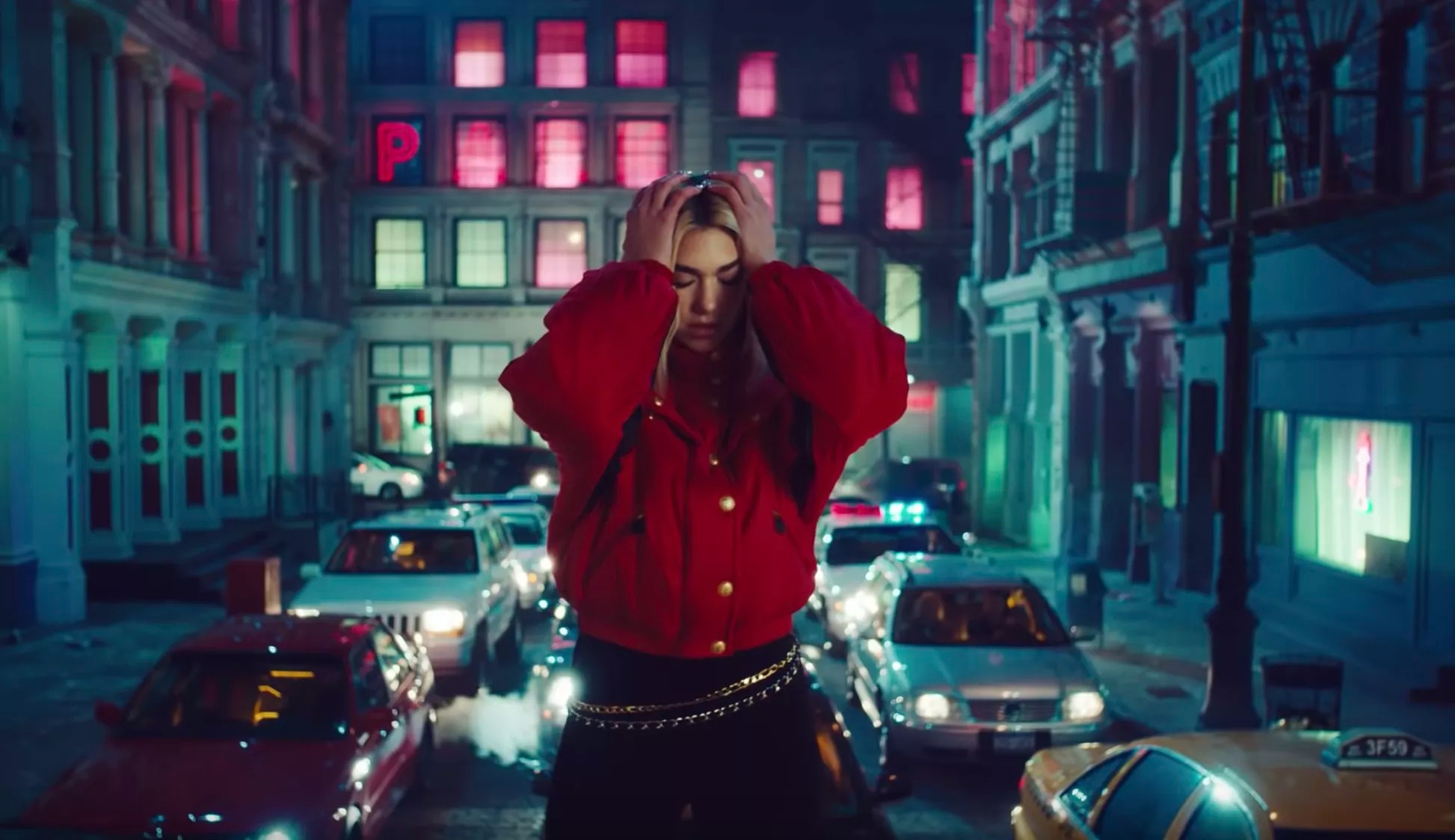 Dua Lipa mặc áo phao màu đỏ, quần bó đen, đeo thắt lưng xích trong MV Break My Heart