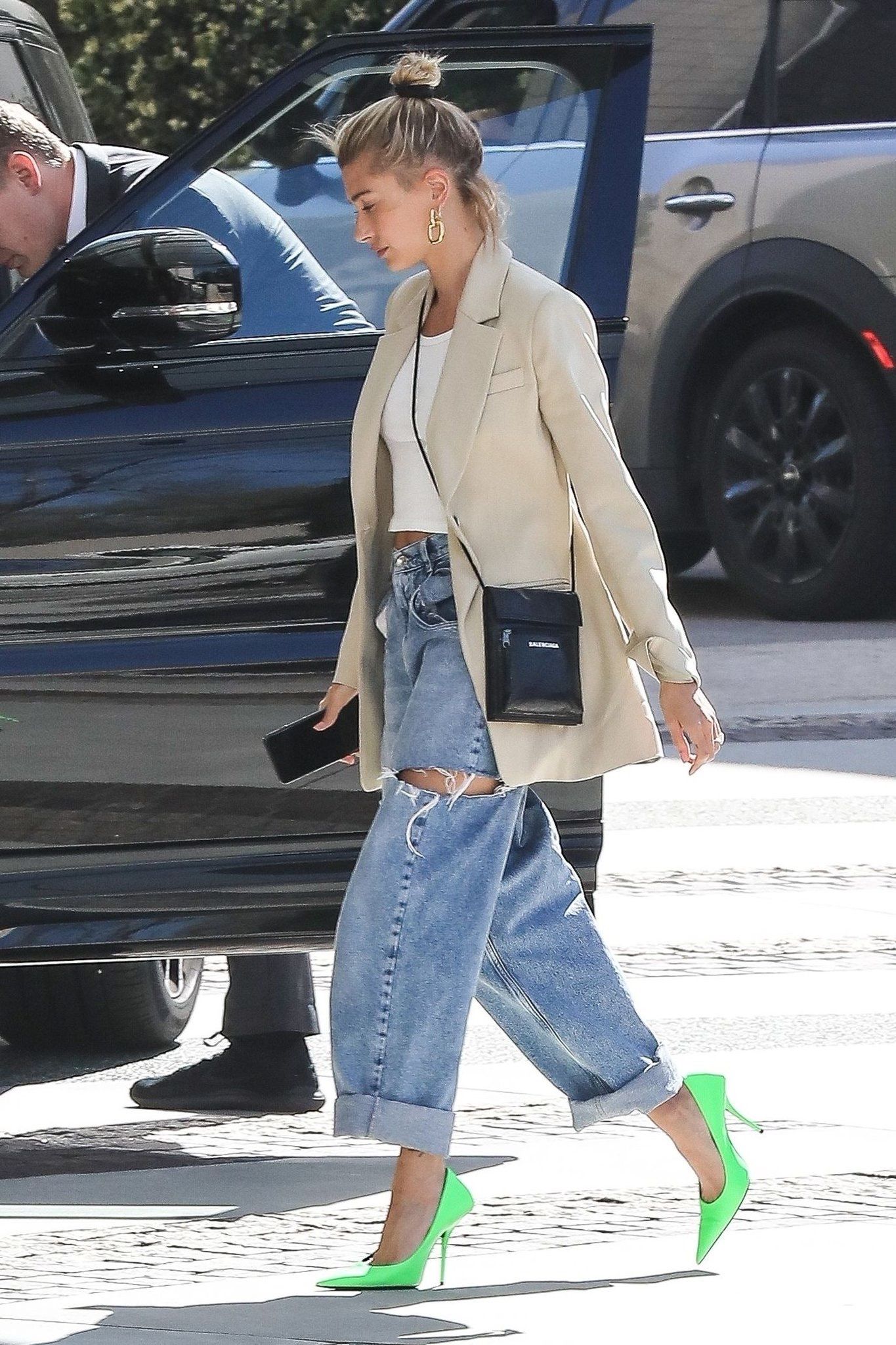 Hailey Bieber mặc quần jeans rách, áo blazer và mang giày cao gót xanh neon