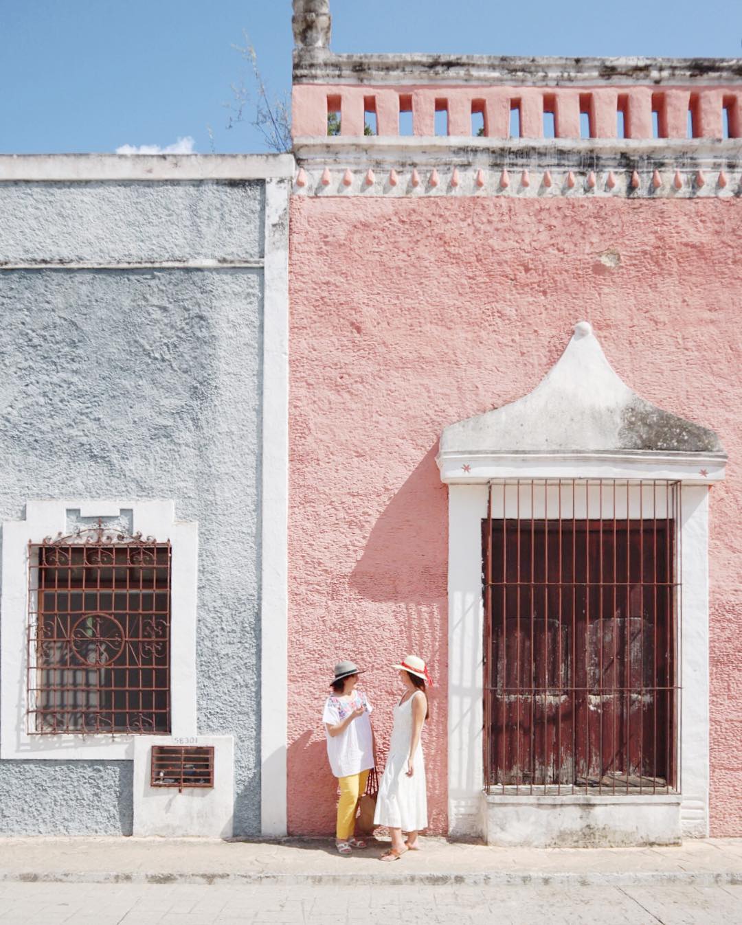 pastel hai cô gái đứng trước tòa nhà màu hồng