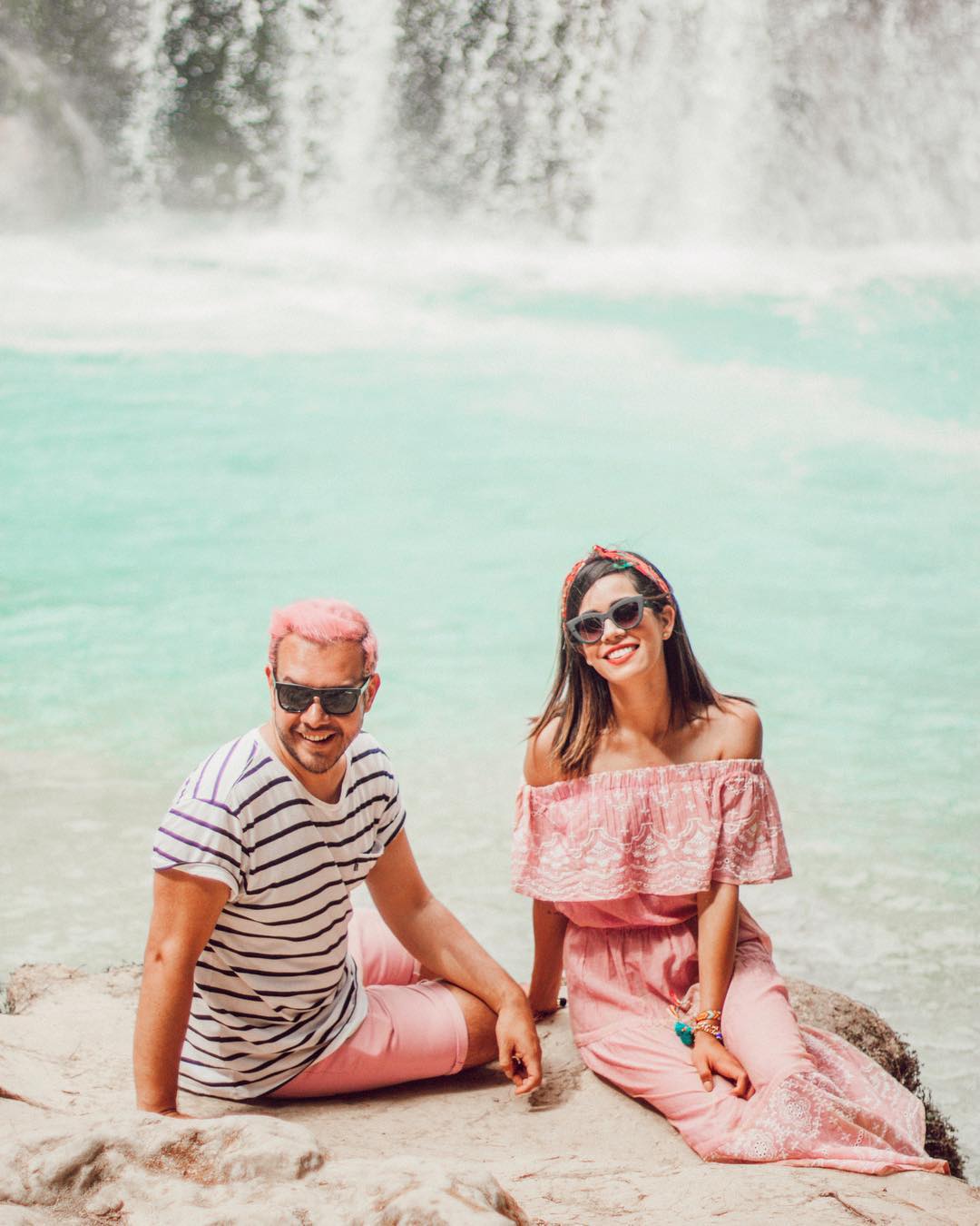 pastel hai người ngồi bên cạnh thác nước