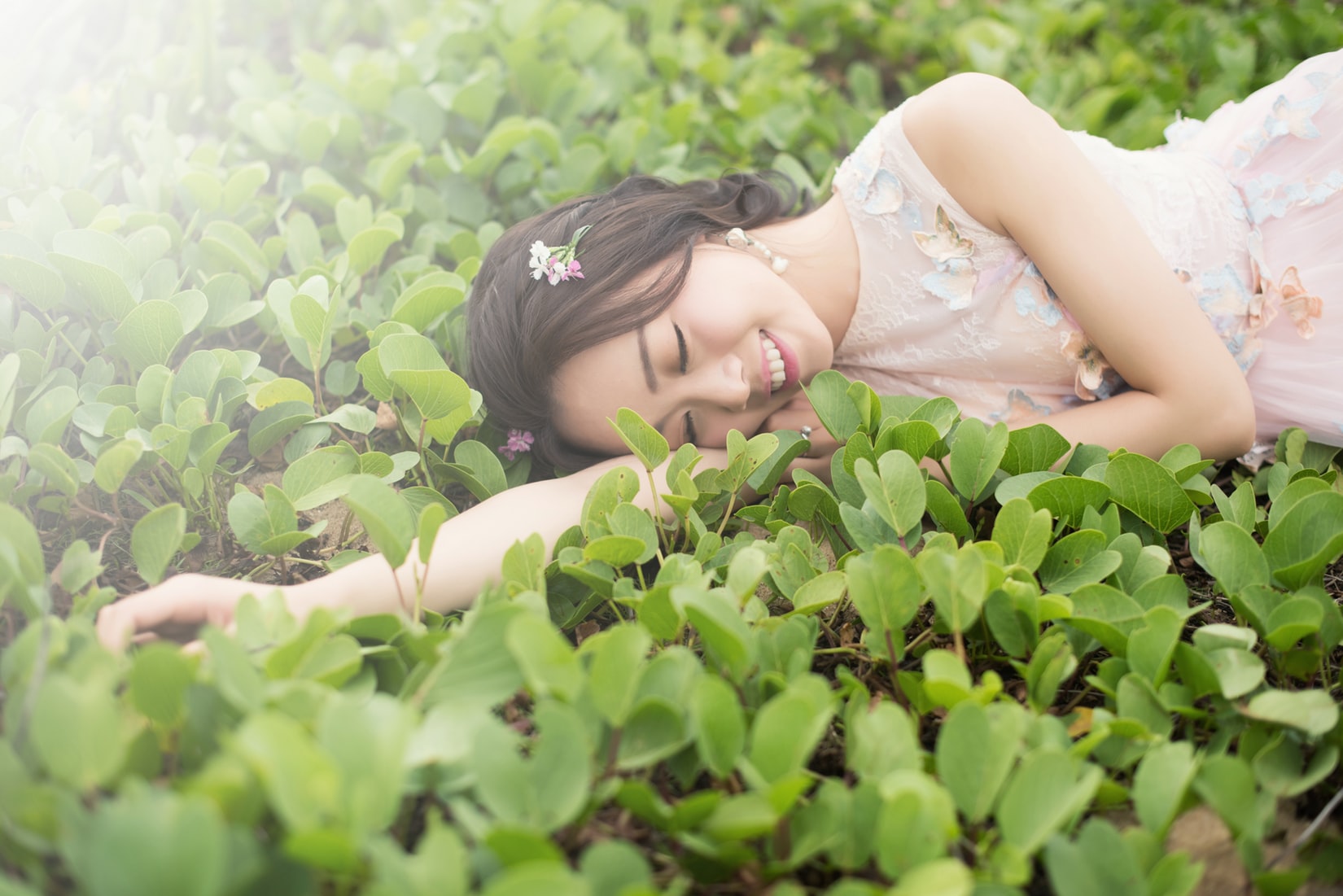 Cô gái nằm trên nền cây lá xanh tươi, dưỡng da