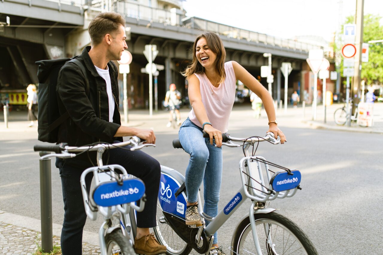 chàng trai và cô gái nhìn nhau cười bên xe đạp 