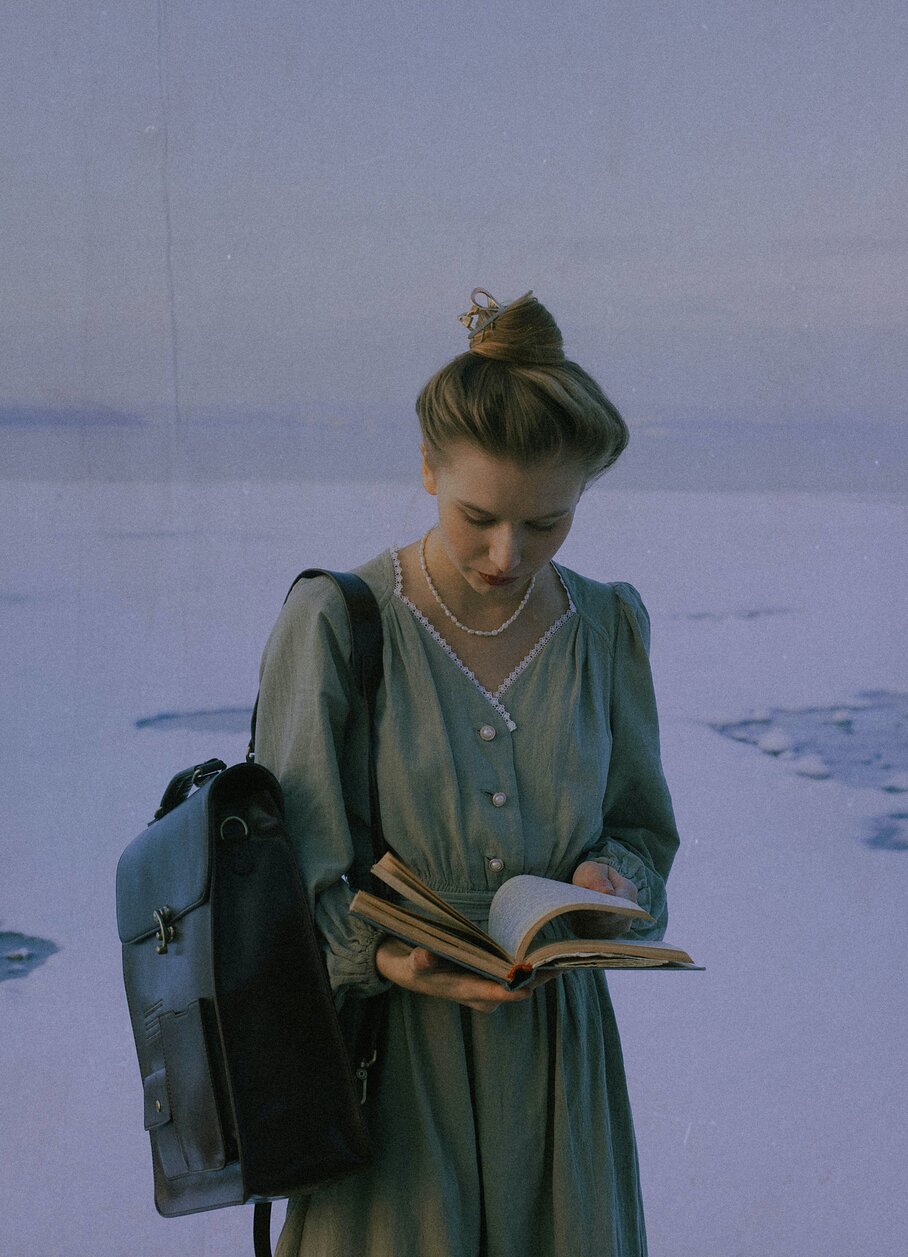 cô gái đeo balo đọc sách bên biển 
