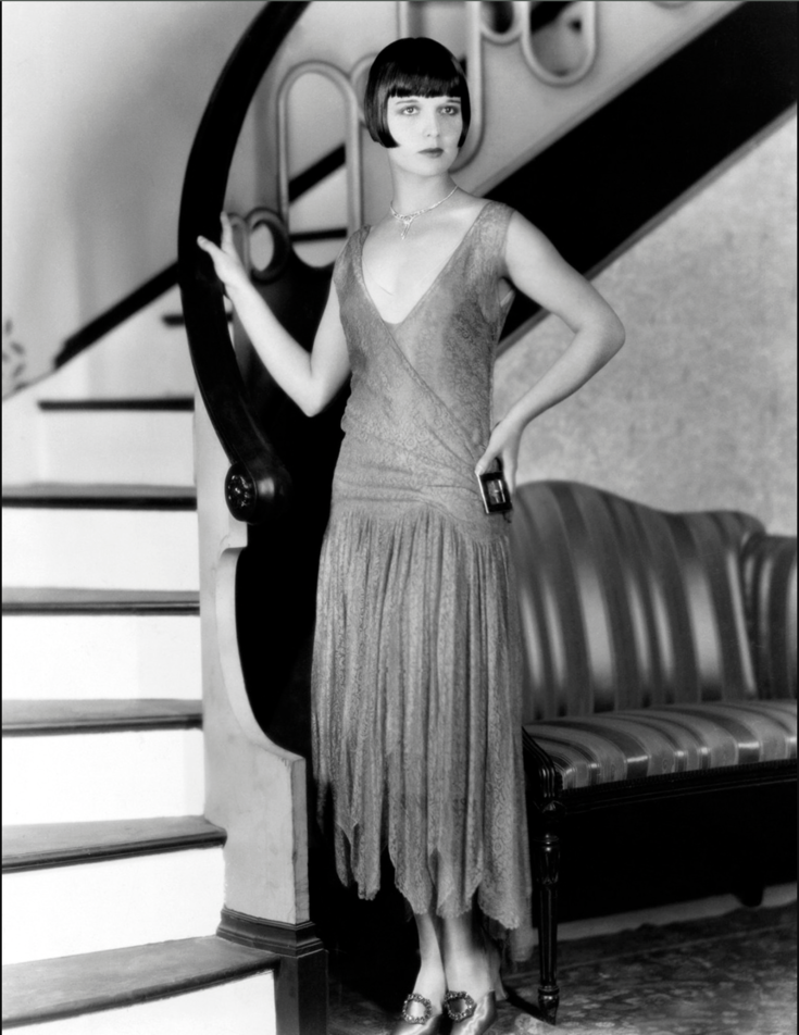 woman in flapper style standing next to the stairs in black and white