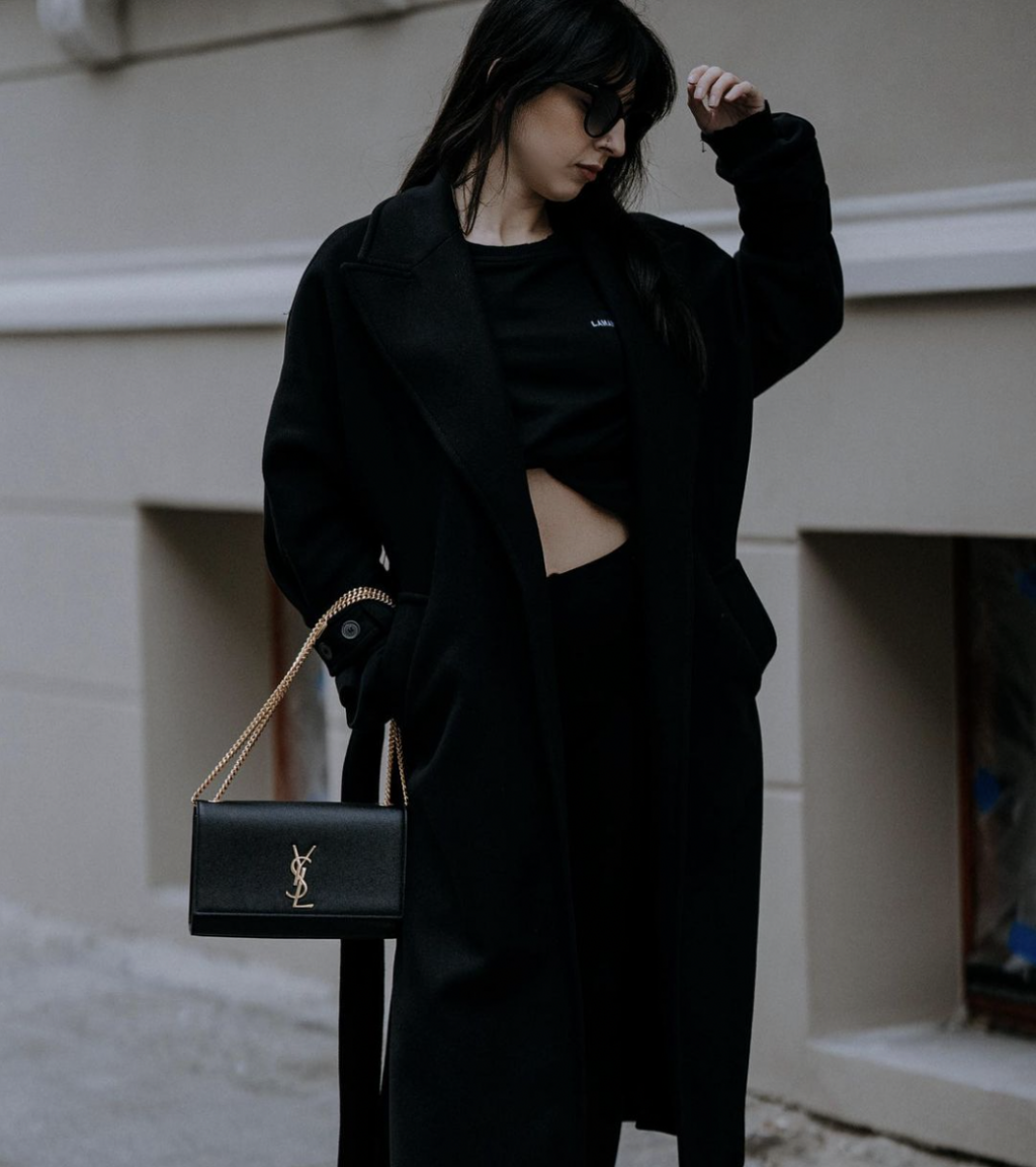 Outift đen và túi YSL đen trước background kem