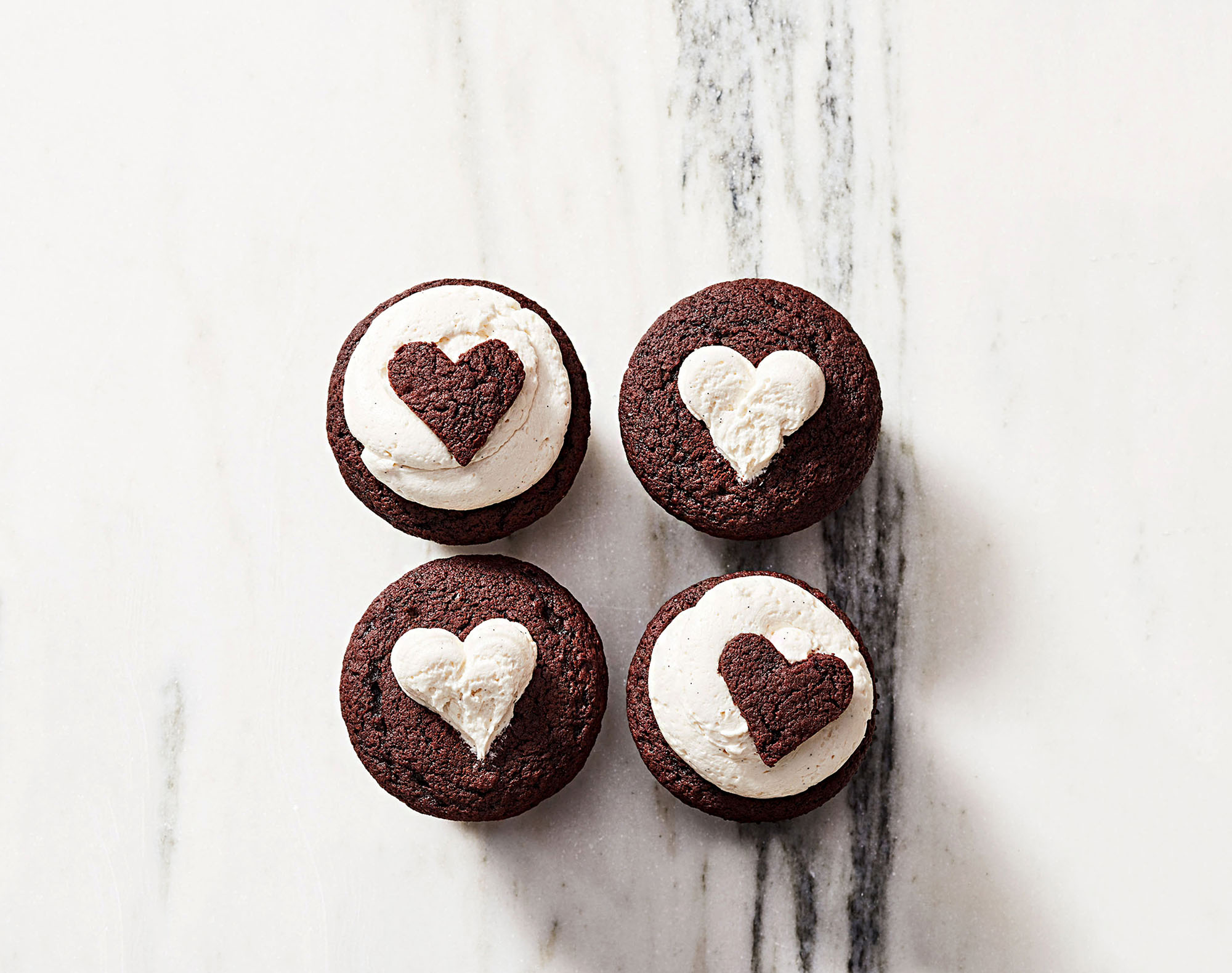 4 chiếc bánh cupcake được phủ kem tươi bên trên có họa tiết hình trái tim valentine