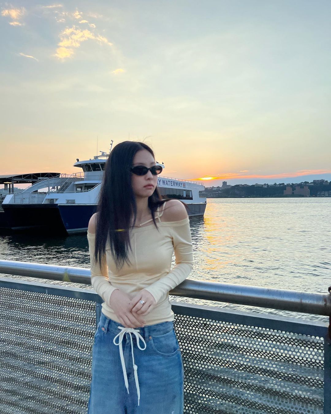 Jennie áo trễ và vàng cùng quần jeans xanh 