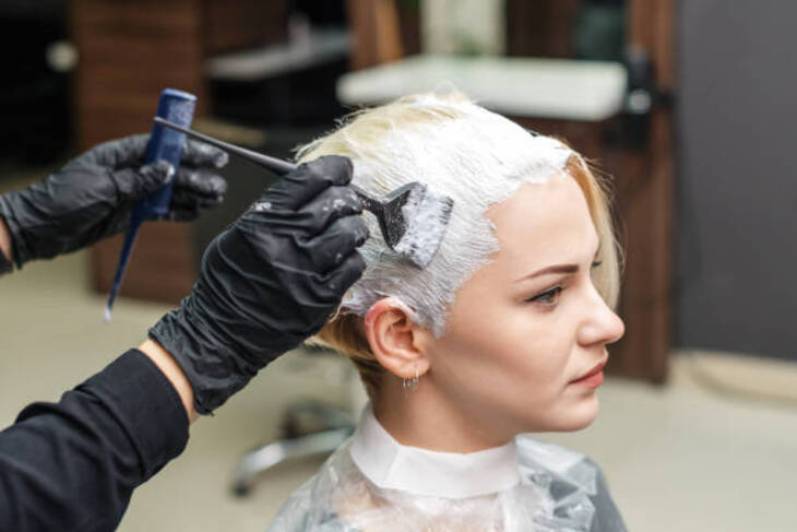 Tác hại của việc tẩy tóc. Ảnh: Getty Images. Cô gái đang tẩy tóc ở salon.