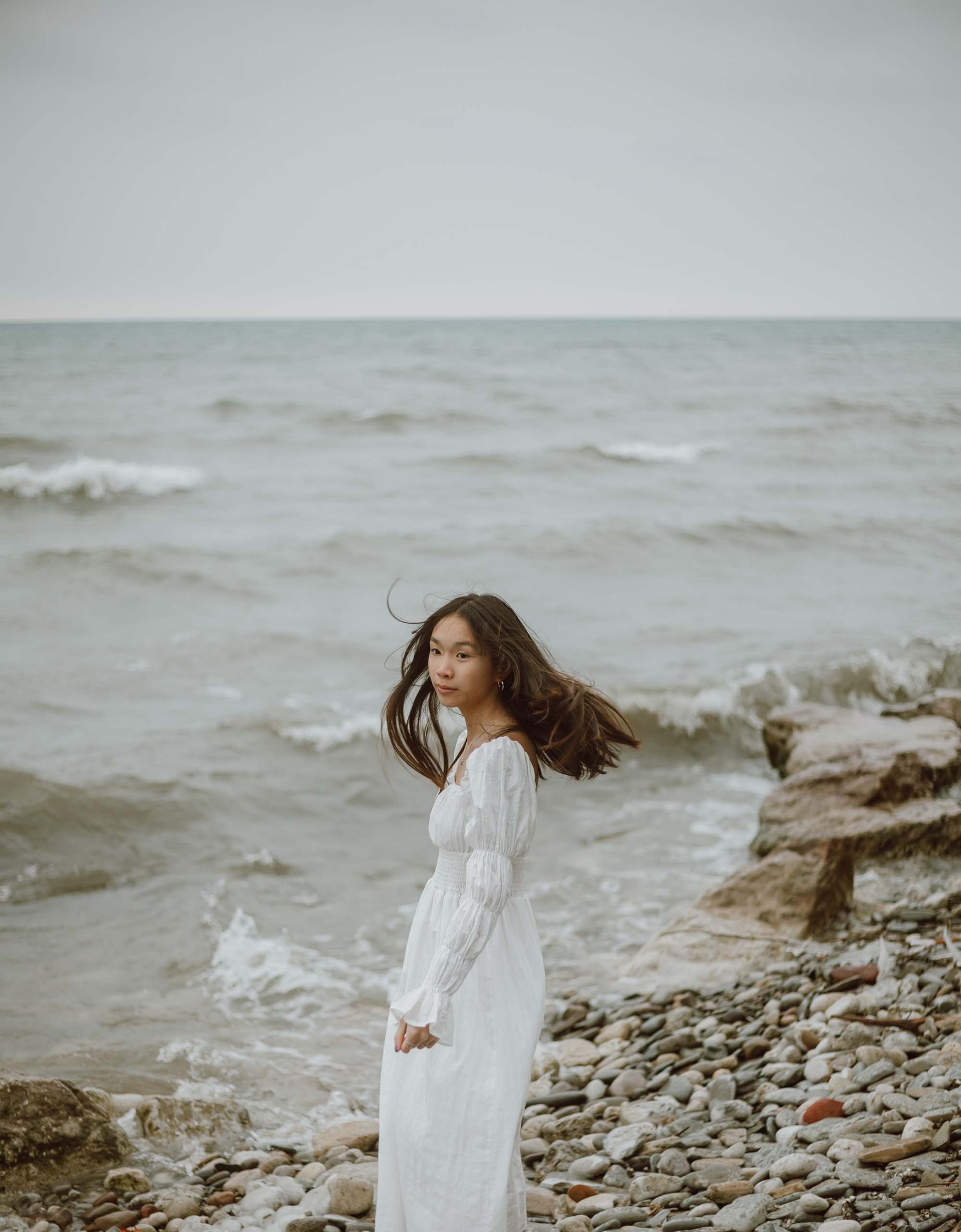 cô gái mặc váy trắng đứng trước biển