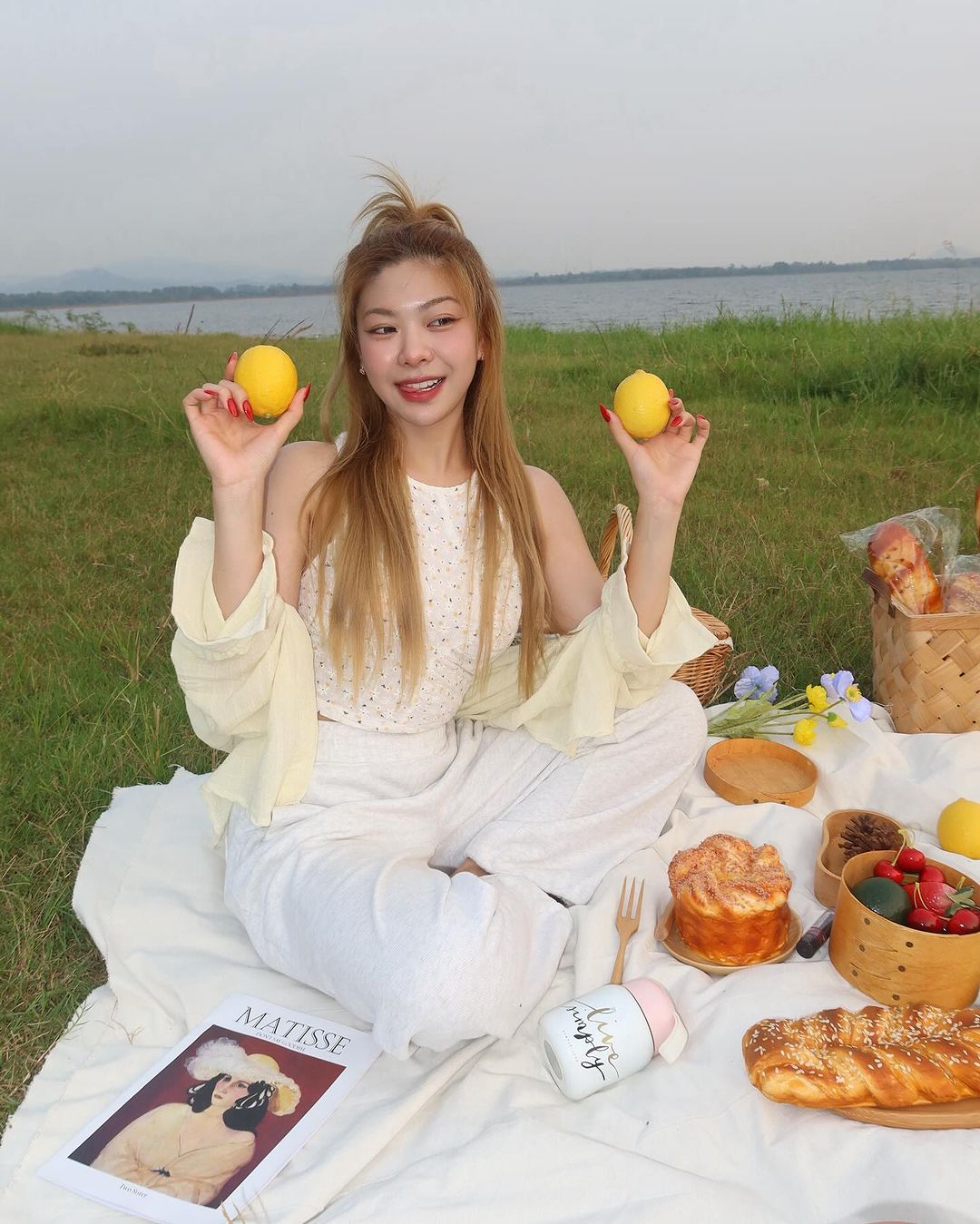 cô gái xinh đẹp cầm hai quả chanh đi picnic